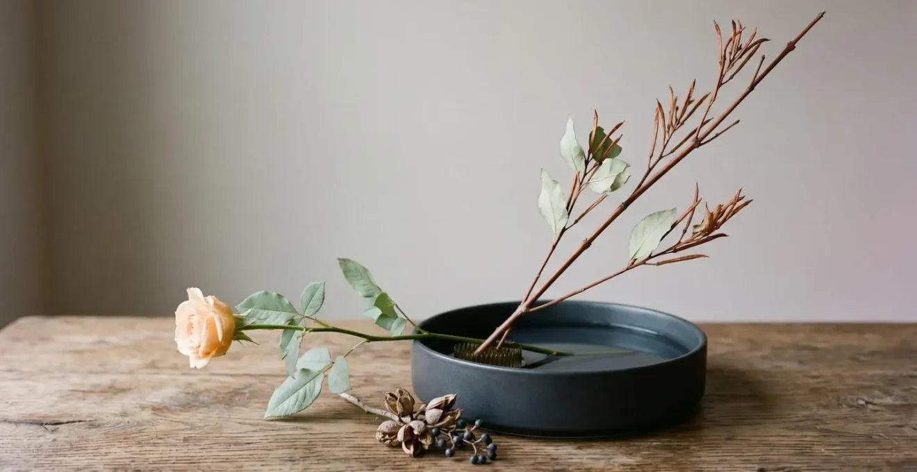 Vue de trois-quarts d'une composition ikebana minimaliste avec trois tiges disposées de manière asymétrique créant des lignes de force dynamiques